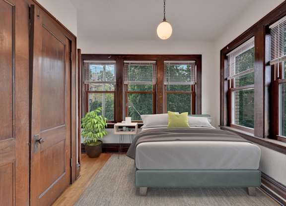 A bedroom with a bed, nightstand, and window.