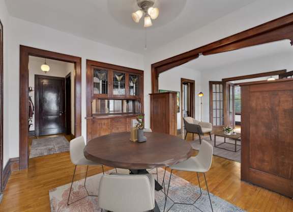 A dining room with a round wooden table surrounded by white chairs.