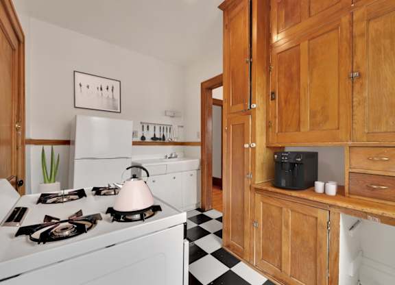 A kitchen with a white stove top oven and wooden cabinets.