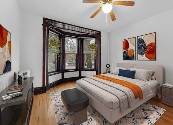 A bedroom with a bed, a chair, and a ceiling fan.
