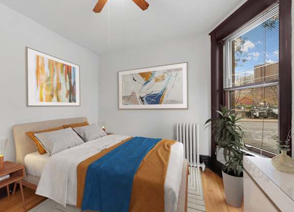 A bedroom with a bed, a ceiling fan, and two pieces of artwork on the wall.