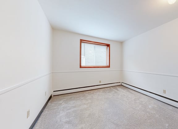 a bedroom with white walls and a window