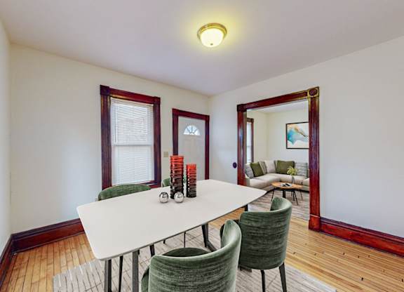 A dining room with a white table and green chairs.