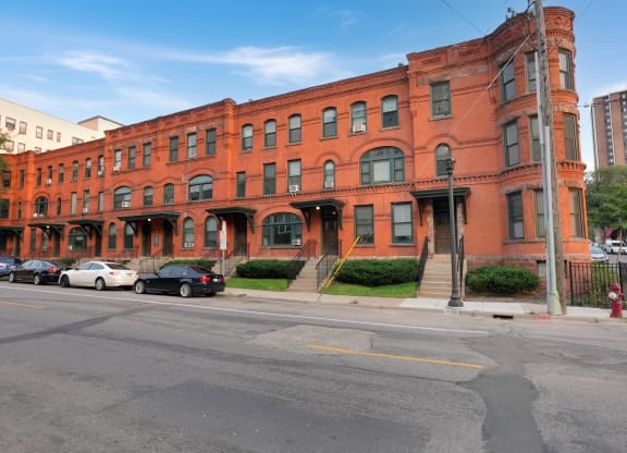 a red brick building on a street corner with cars parked in front of it