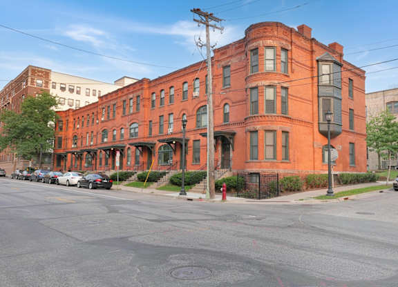 A red brick building with a black fence in front.