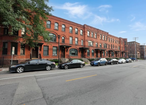 a row of red brick buildings with cars parked in front of them
