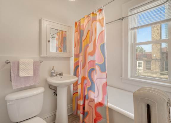 A bathroom with a toilet, sink, and shower curtain.