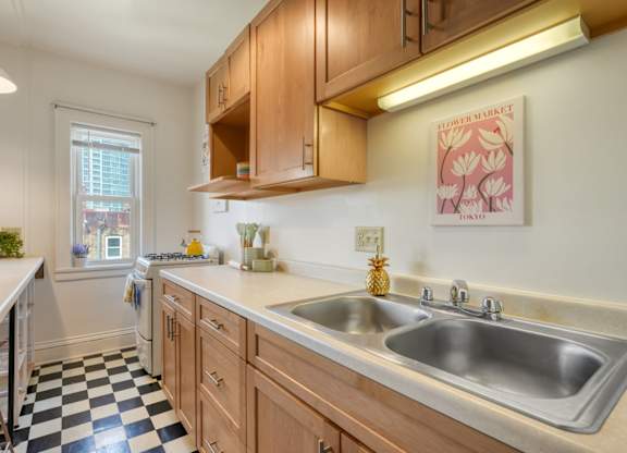 A kitchen with a checkered floor and wooden cabinets.