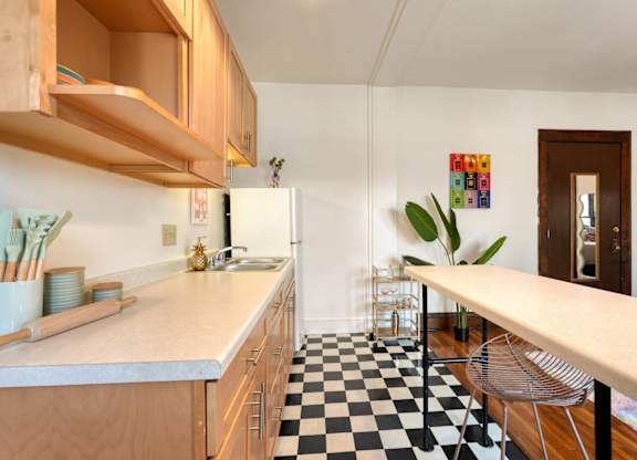 A kitchen with a checkered floor and wooden cabinets.