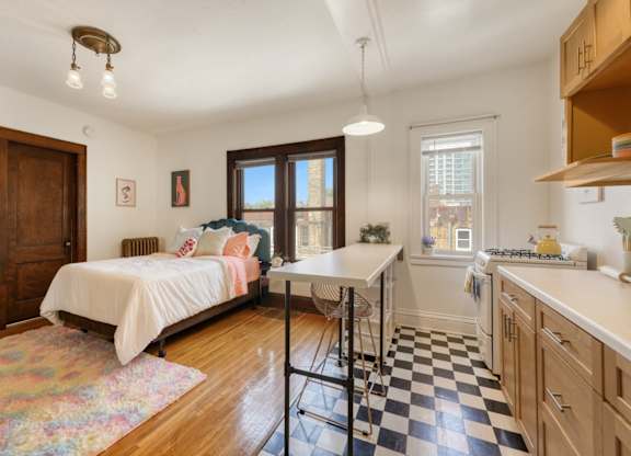 A bedroom with a bed, a desk, and a checkered floor.