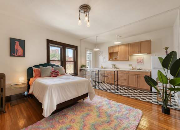 A bedroom with a bed, a chair, and a painting of a giraffe on the wall.