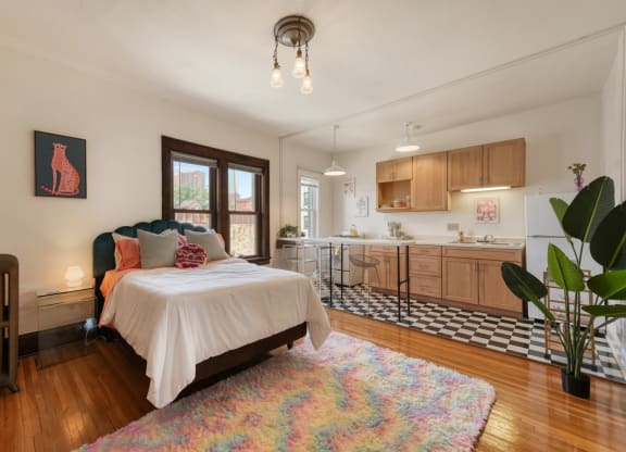 a bedroom with a bed and a kitchen in the background
