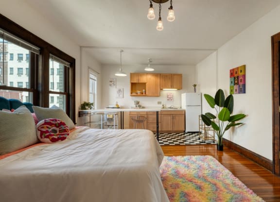 a bedroom with a bed and a kitchen in the background