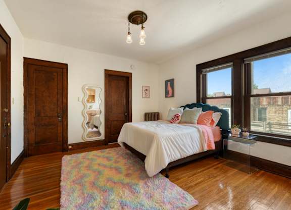 A bedroom with a bed, a rug, and a window.
