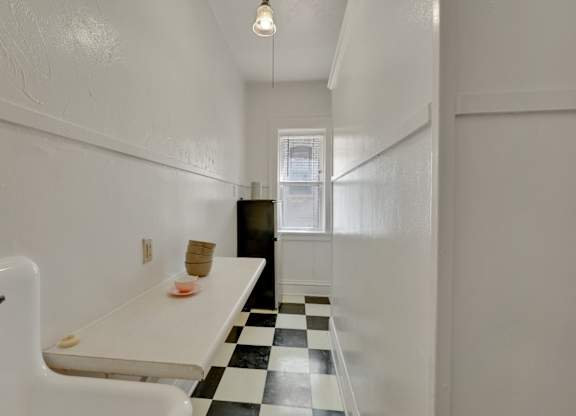A white sink in a small bathroom with a black and white checkered floor.