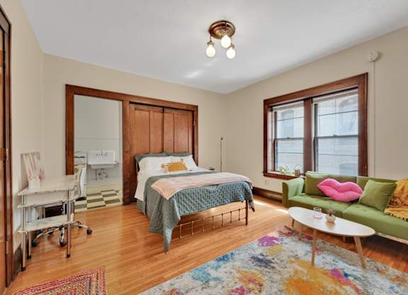 A bedroom with a bed, a couch, and a chair.