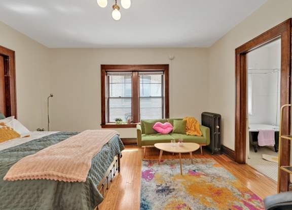 A bedroom with a bed, a green chair, and a window.