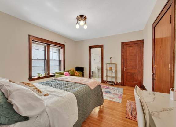 A bedroom with a bed, a chair, and a table.
