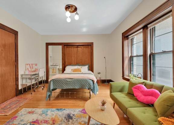 A bedroom with a bed, a couch, and a rug.