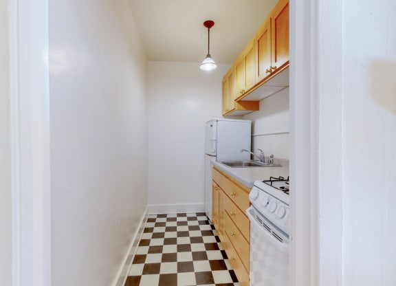 A Cozy Kitchen with Wood Cabinets and Black and White Checkered Flooring at The PArk Apartments in Minneapolis, MN