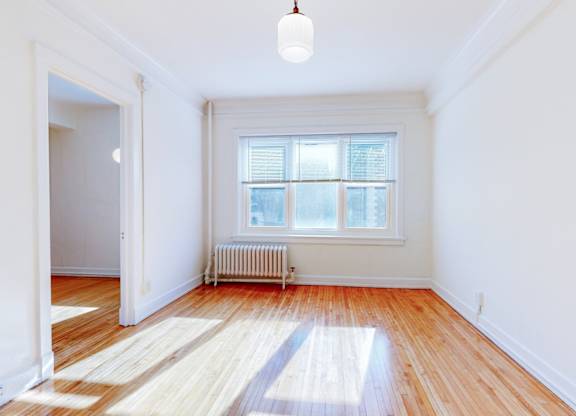 A room with a window and a radiator on the floor.