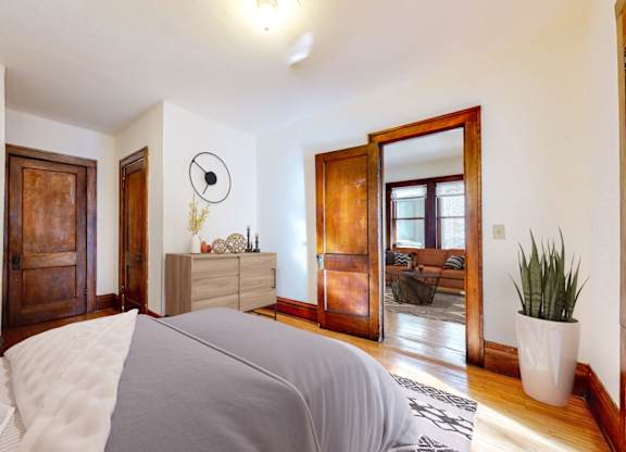 A bedroom with a bed in the foreground and a wooden door in the background.