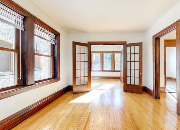 A room with wooden floors and white walls has a large wooden door in the center.