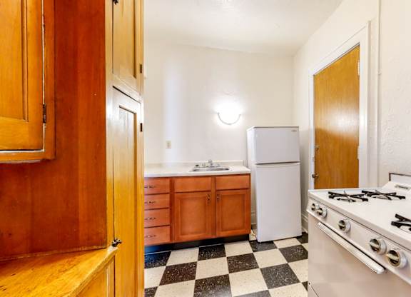 A kitchen with a white stove top oven and a checkered floor.