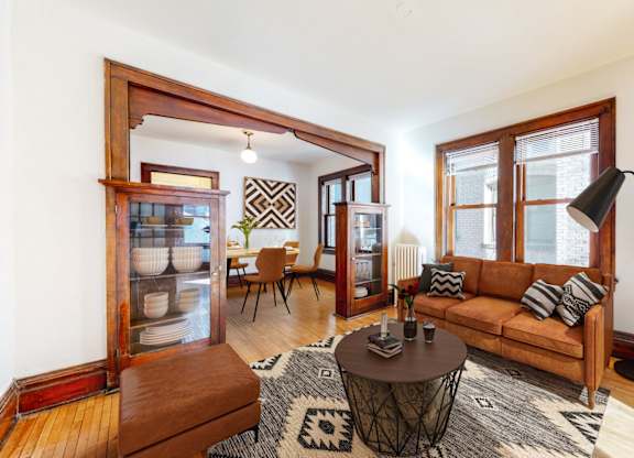 A living room with a brown couch, a coffee table, and a rug.