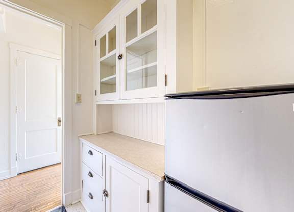 A kitchen with white cabinets and a black fridge.