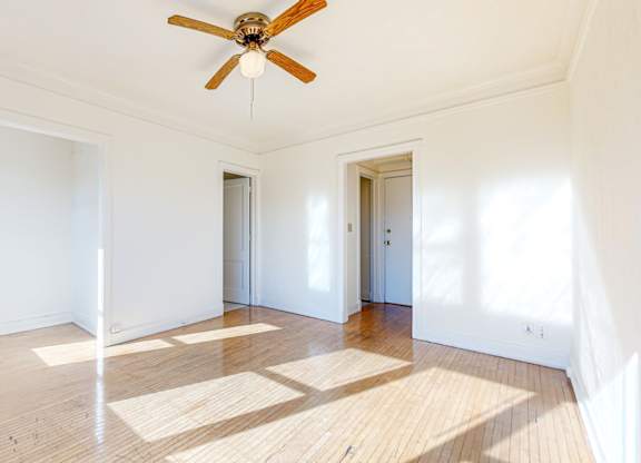 A room with a ceiling fan and wooden flooring.