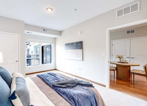 A bedroom with a large bed and a balcony outside.