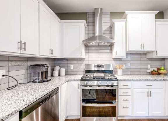 A modern kitchen with white cabinets and stainless steel appliances.