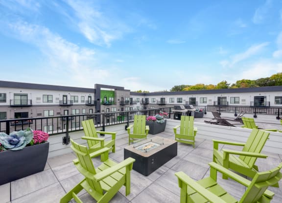 a rooftop patio with green chairs and patio furniture