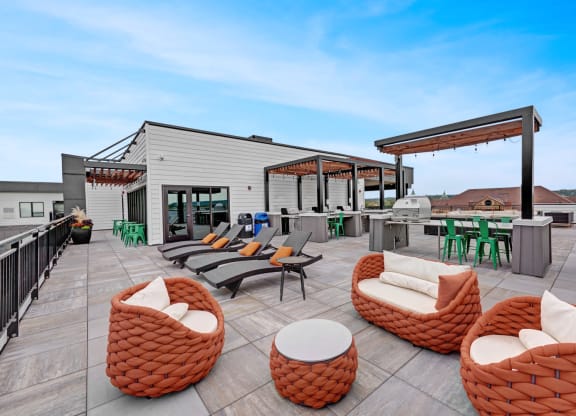 a rooftop patio with chairs and tables and a building in the background