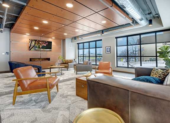 club room with chairs and couches, a fireplace, flat screen tv, and large windows