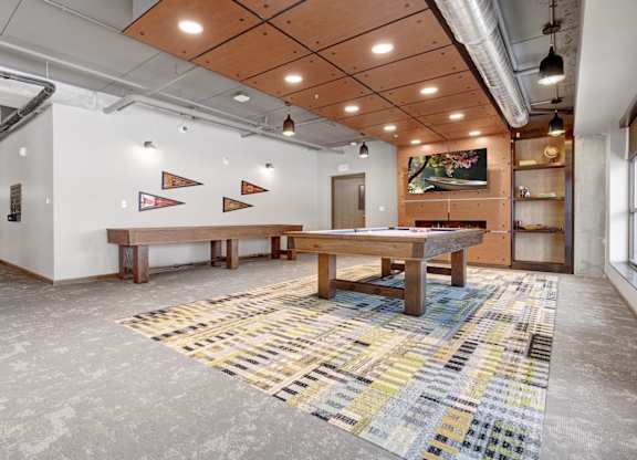 a game room with a shuffle board table, pool table, and a flat screen tv