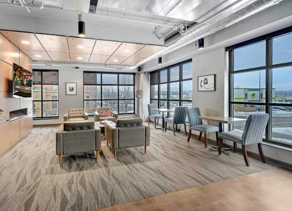 A communcal business center filled with lounge furniture, large windows, and a flat screen tv