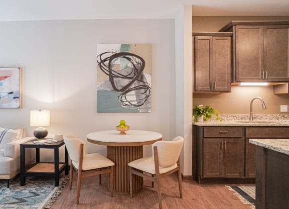 a living room with a table and chairs and a kitchen in the background at The Yards and Backyards, MN 55075