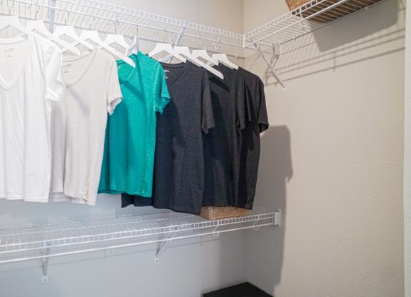 a rack of shirts hanging on a clothes rack in a closet