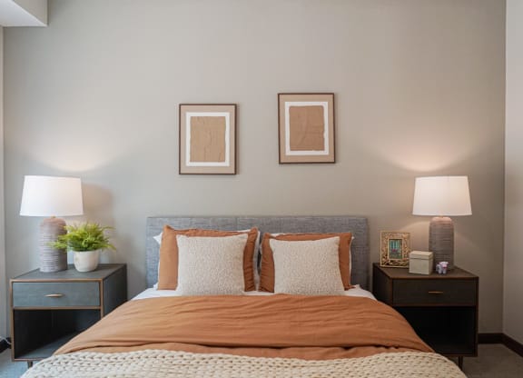 a bedroom with a bed and two lamps and pictures on the wall