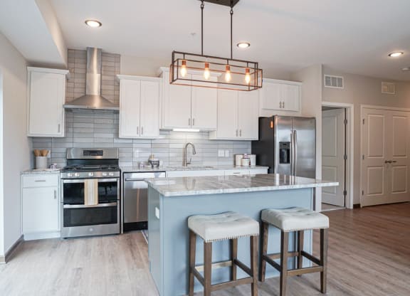 a kitchen with white cabinets and a blue island with three stools