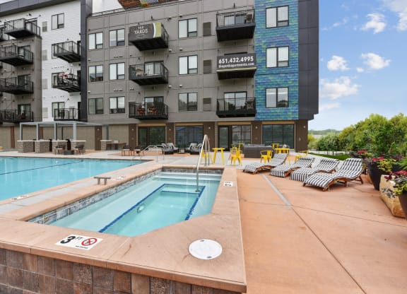 a swimming pool with lounge chairs in front of an apartment building