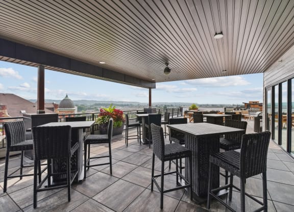 a rooftop patio with tables and chairs and a view of the city