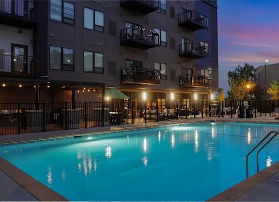 A swimming pool in front of a building at dusk.