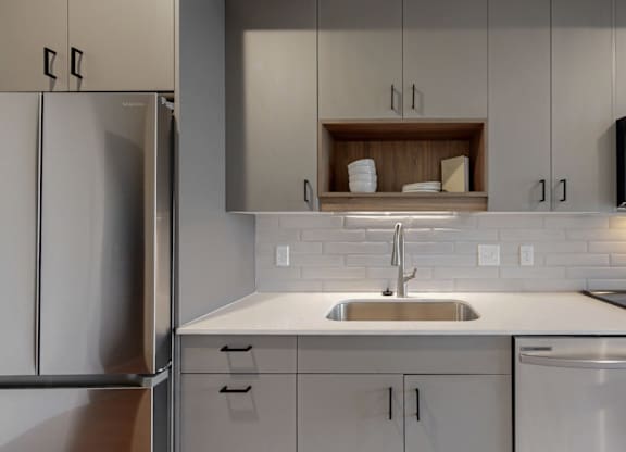 A modern kitchen with a stainless steel refrigerator, a white sink, and a microwave above the stove.at Tyler Street Stacks, Minneapolis, MN 55413