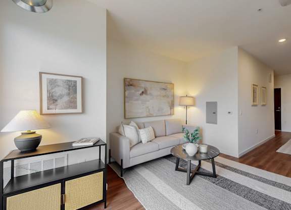 A living room with a white couch, a coffee table, and a lamp.at Tyler Street Stacks, Minneapolis