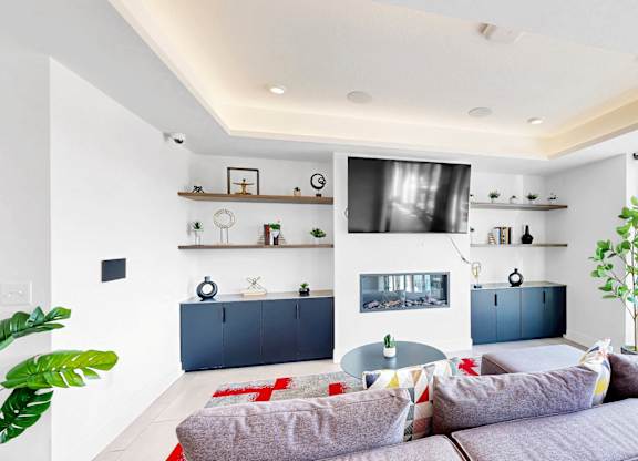 A modern living room with a grey sofa and a red rug.