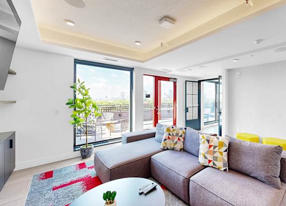 A living room with a grey couch and a glass table.