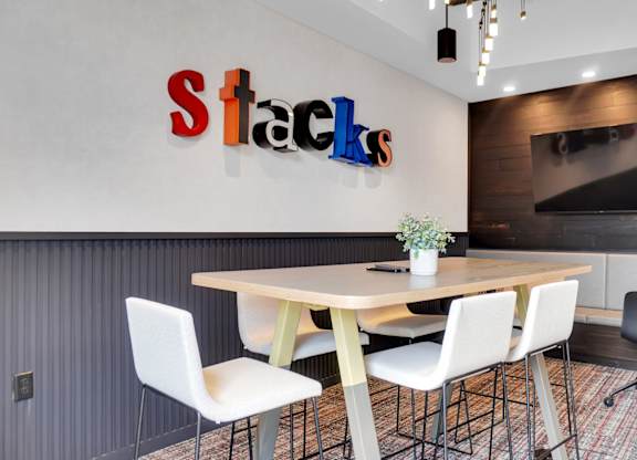 A conference room with a table, chairs, and a sign that says Stacks.